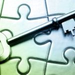 old fashioned key placed on top of several connected jigsaw puzzle pieces