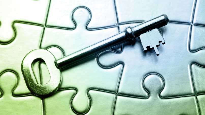 old fashioned key placed on top of several connected jigsaw puzzle pieces