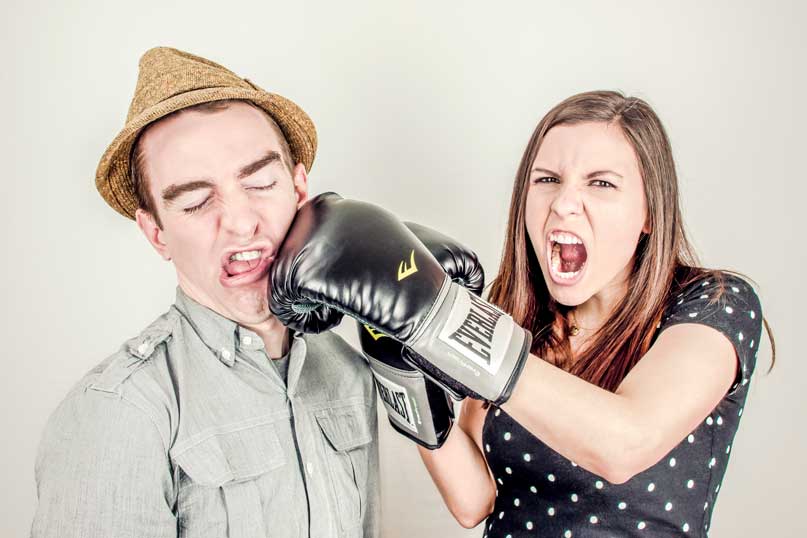 woman with boxing glove hitting man in the mouth