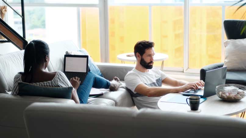 Man and women in living room working on their laptops