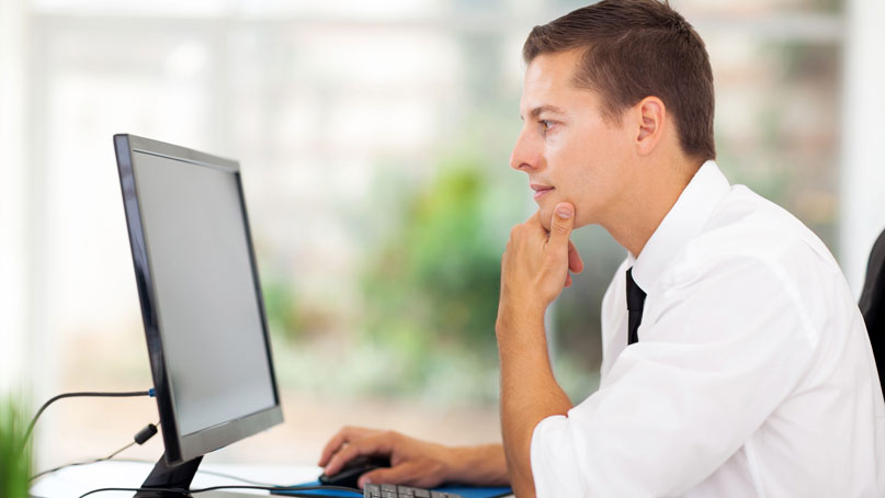 man sitting and looking at a computer screen