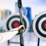 woman shooting bow and arrow at target