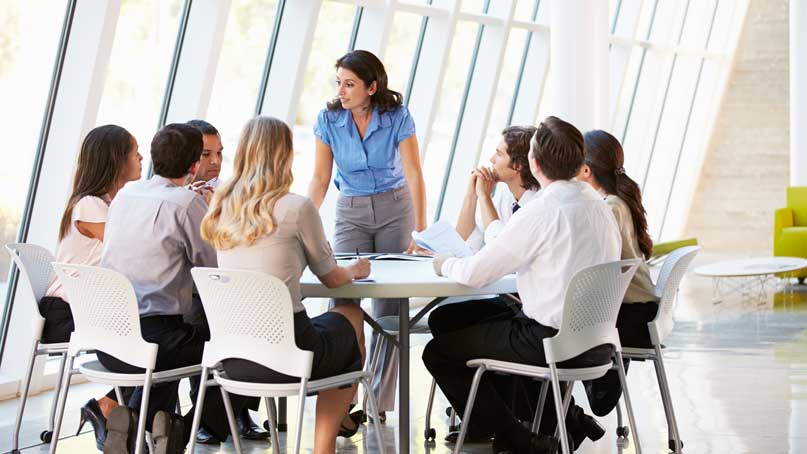 woman standing at a table filled with work colleagues